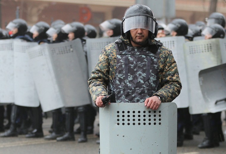 Image: A Kazakh law enforcement officer stands guard during a protest triggered by fuel price increase in Almaty