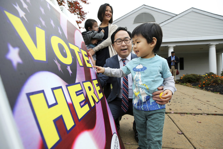 Then-candidate Andy Kim plays a word-game with his son as his wife, Kammy Lai, looks on with their younger son outside a polling place in Bordentown, N.J., on Nov. 6, 2018.