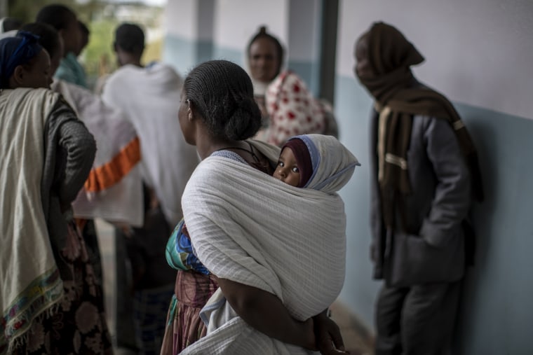 A baby sits on his mother's back as they wait to see a visiting doctor at a hospital that was damaged and looted by Eritrean soldiers who used it as a base, according to witnesses in Hawzen.