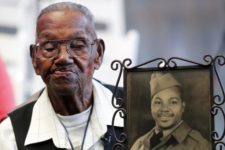 World War II veteran Lawrence Brooks holds a photo of him taken in 1943, as he celebrates his 110th birthday at the National World War II Museum in New Orleans, on Sept. 12, 2019.  Brooks, the oldest World War II veteran in the U.S. — and believed to be the oldest man in the country — died on Wednesday, Jan. 5, ,2022 at the age of 112.
