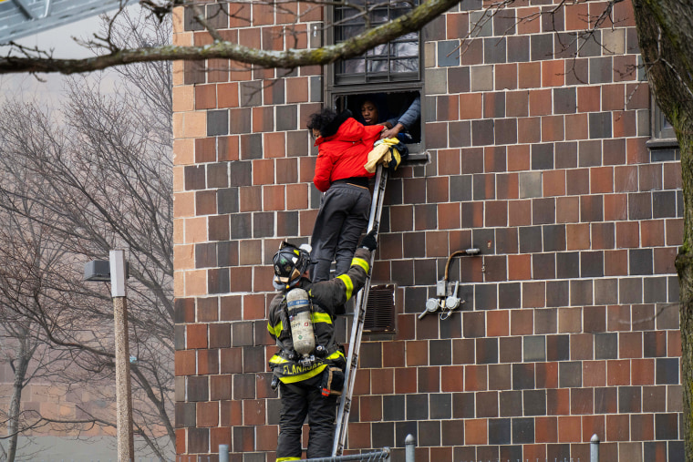 Image: Firefighters hoist a ladder to rescue people through their windows after a fire broke out in the Bronx, N.Y., on Jan. 9, 2022.