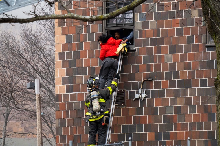 Firefighters hoist a ladder to rescue residents after a fire broke out inside a third-floor duplex apartment in the Bronx, N.Y. on January 9.