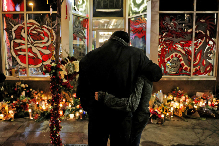 Image: People attend a candlelight vigil to remember tattoo artist who died during a mass shooting in Denver