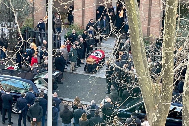 People gather around a casket draped with the Nazi flag outside a church in Rome on Monday.