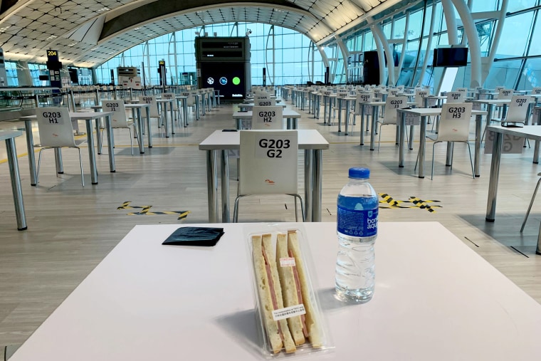 Passengers arriving at Hong Kong International Airport are assigned desks at an unused gate while they wait for their Covid test results.