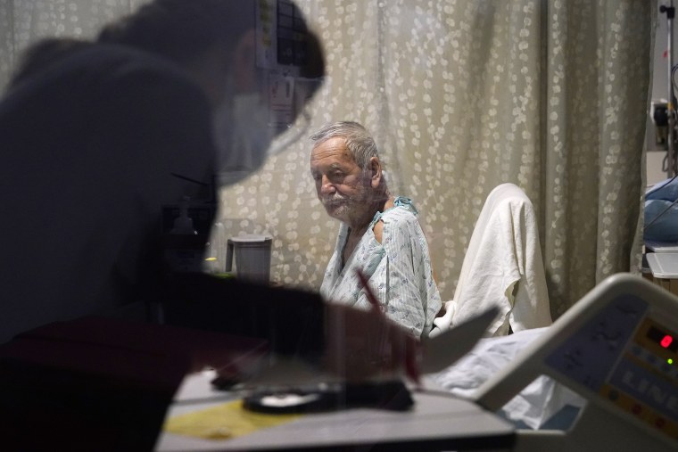 Jesus Aguirre Medina, a Covid-19 patient with a nutritionist looking over paperwork in his room in the acute care unit of Harborview Medical Center, on Friday.