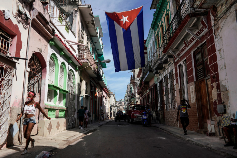 People walk under a Cuban flag hanging in downtown Havana on Oct. 8, 2021.
