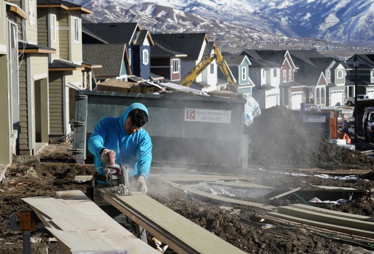 Image: A worker prepares siding to install on a single family home under construction in Lehi, Utah, on Jan. 7, 2022.