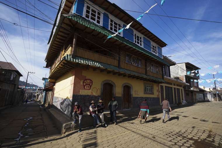 Image: Residents gather on a street corner next to a home built with money earned in the United States, in the Puerpecha Indigenous community of Comachuen, Mexico, on Jan. 19, 2022.