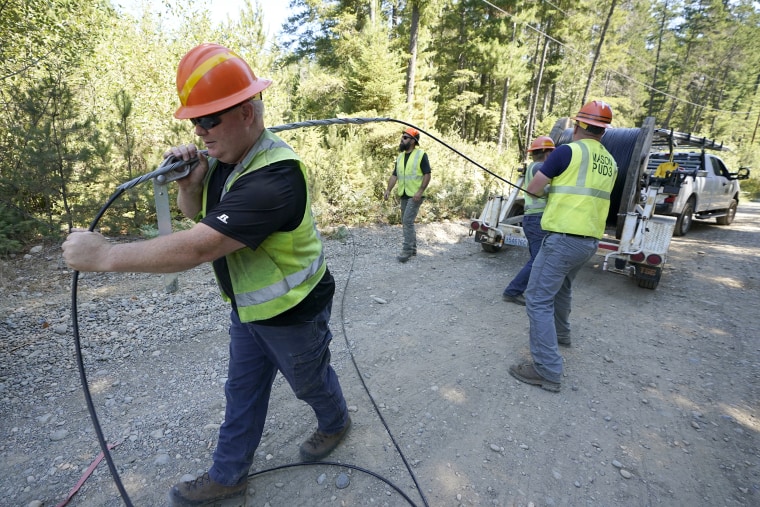 Workers install broadband internet service last summer to homes in a rural area surrounding Lake Christine near Belfair, Wash.