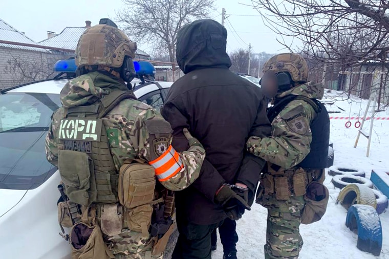 Police officers detain a man outside a munitions facility in the central Ukrainian city of Dnipro, after five people were shot dead.