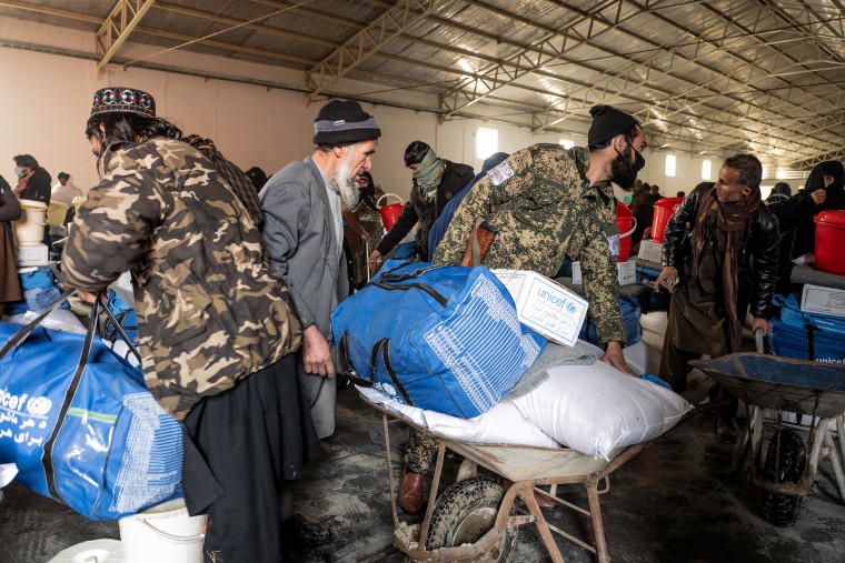 Taliban soldiers assist Afghans at a UNICEF distribution center in Kabul. 