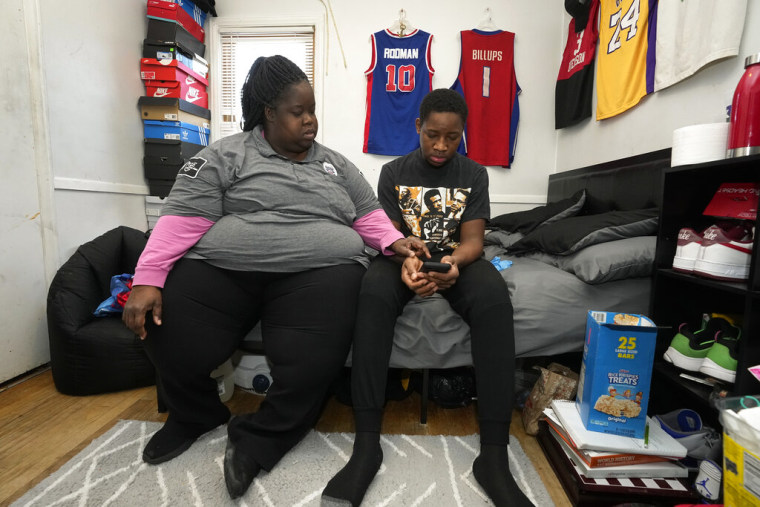 LaTonya Peterson se sienta junto a su hijo Joshua Jackson, de 16 años, mientras este asiste a clases virtuales desde su casa en Detroit.