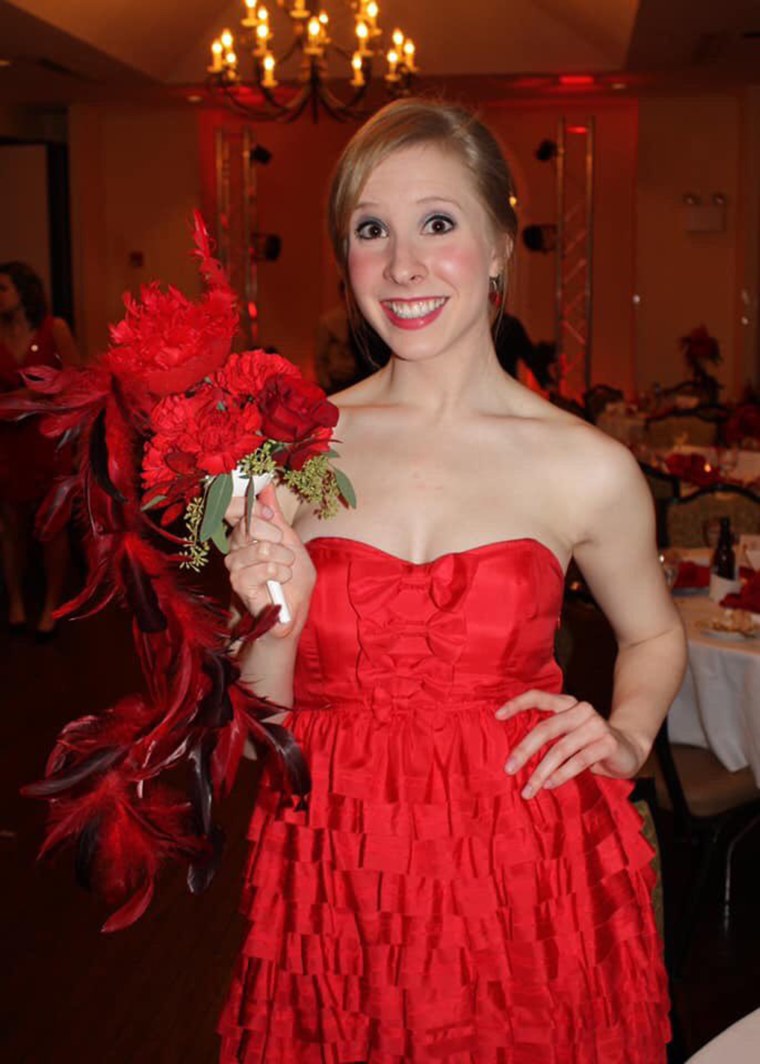 Alison Parker smiles while holding red flowers that match her strapless dress.