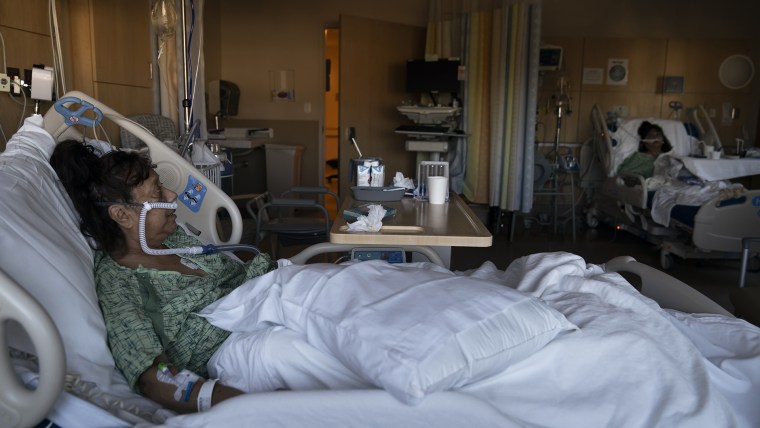 Natalie Balli, de 71 años, y su hermana gemela, Linda Calderon, al fondo, son vistas en sus camas en la unidad de COVID-19 en el Providence Holy Cross Medical Center en Los Ángeles.
