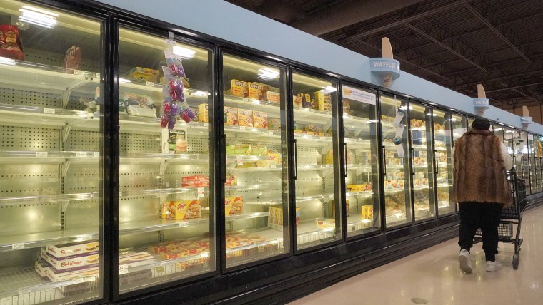 Una compradora pasa delante de los refrigeradores de alimentos congelados parcialmente vacíos en una tienda en Pennsylvania.