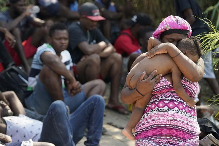 Una mujer migrante sostiene a su hijo mientras espera en un campamento improvisado con otras personas después de cruzar el Río Bravo hacia Estados Unidos desde México, el viernes 17 de septiembre de 2021 en Del Río, Texas.