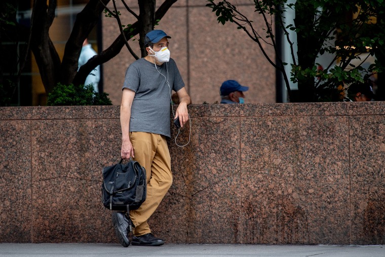 A man wearing an N-95 style mask rests near Times Square as tourism and entertainment start returning to the city on August 09, 2021 in New York City.
