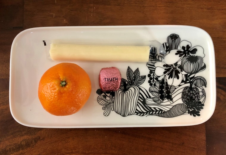 A tangerine with string cheese and a Dove Promise square. 