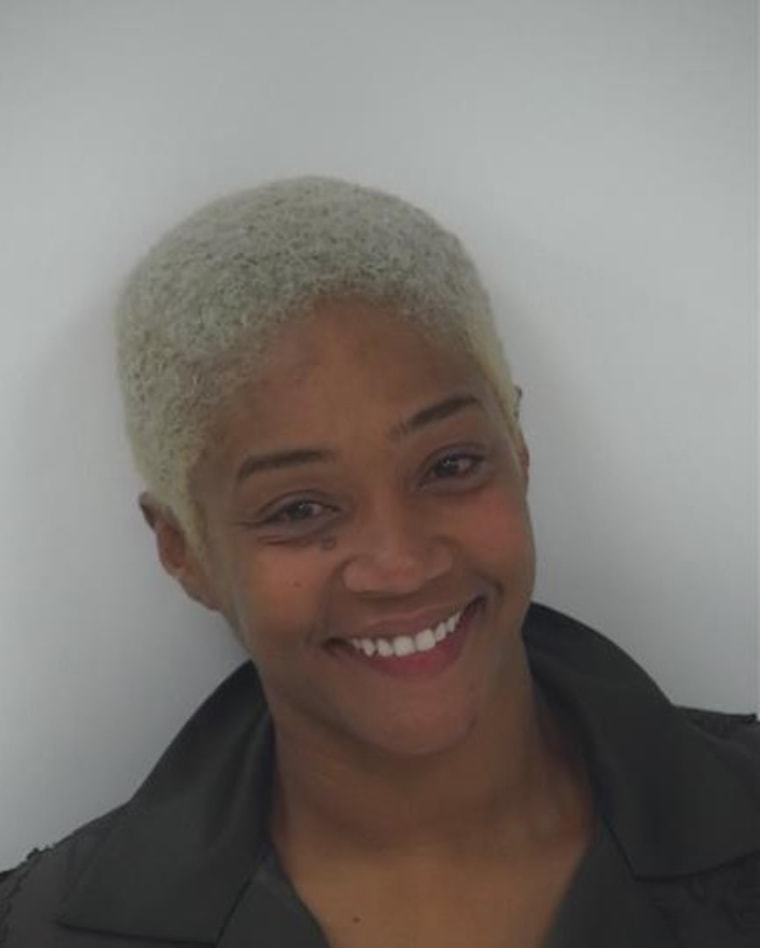 Haddish smiles in front of a white wall. Her hair is cut in a short buzz cut and dyed platinum blond.