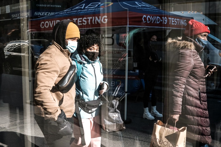 Image: People pass a Covid-19 testing van along a Manhattan street on Jan. 21, 2022 in New York.