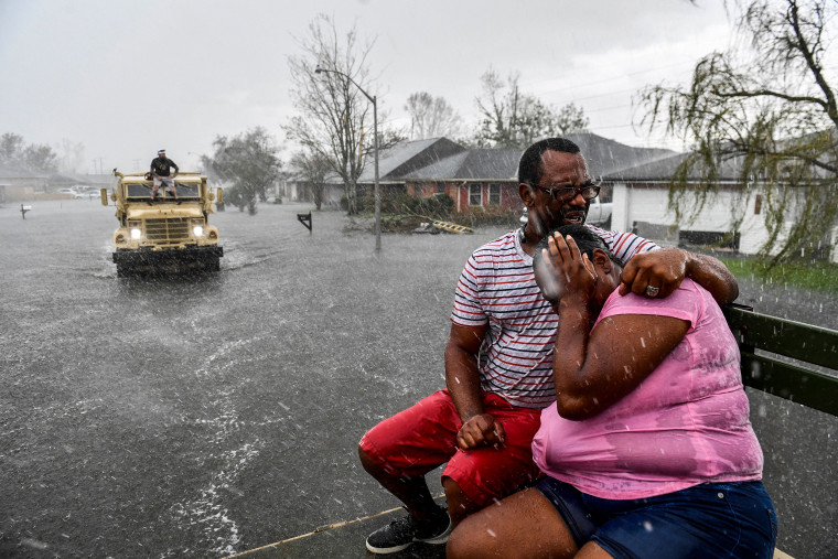 Sudden rain shower soaks a couple with water while riding out of a flooded neighborhood in LaPlace, La., on Aug. 30, 2021 in the aftermath of Hurricane Ida.