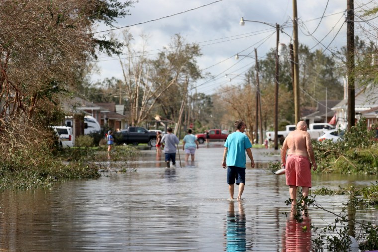 Residents walk down a flooded residential street in the aftermath of Hurricane Ida on Aug. 30, 2021 in Norco, La.