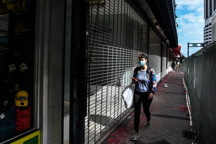 Image: A woman walks past a closed business shop in Miami on Jan. 12, 2022.