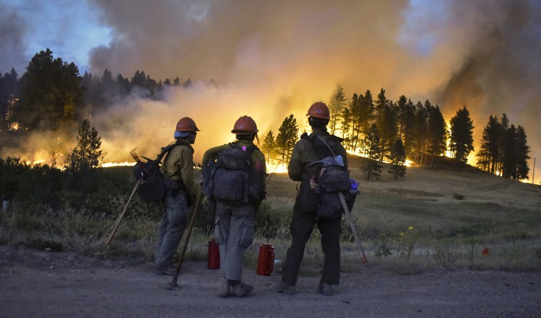 Firefighters watch a hillside burn on the Northern Cheyenne Indian Reservation on Aug 11, 2021, near Lame Deer, Mont., as the Richard Spring fire was threatening hundreds of homes.