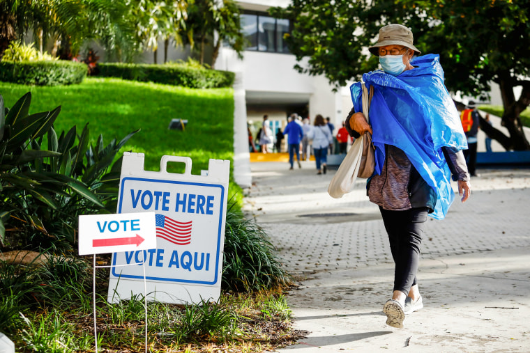 A woman walks past a "Vote Here" sign at Miami Beach City Hall in Miami Beach, Fla., on Oct. 19, 2020.