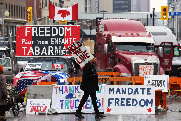 Image: A protester walks in front of parked trucks as demonstrators  protest vaccine mandates implemented by Prime Minister Justin Trudeau on Feb. 8, 2022 in Ottawa, Canada.