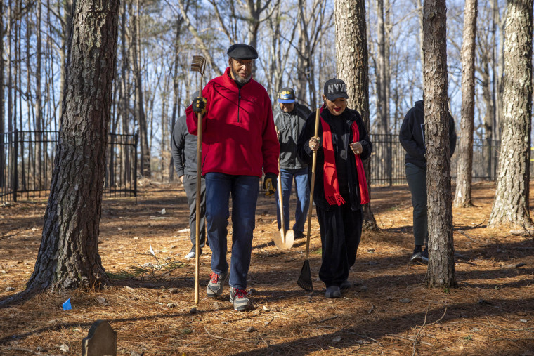 Kirk Canaday, groundskeeper and caretaker of the Macedonia African Methodist Church Cemetery, walks with volunteer Nicole Washington during a visit to the cemetery in Johns Creek, Ga.