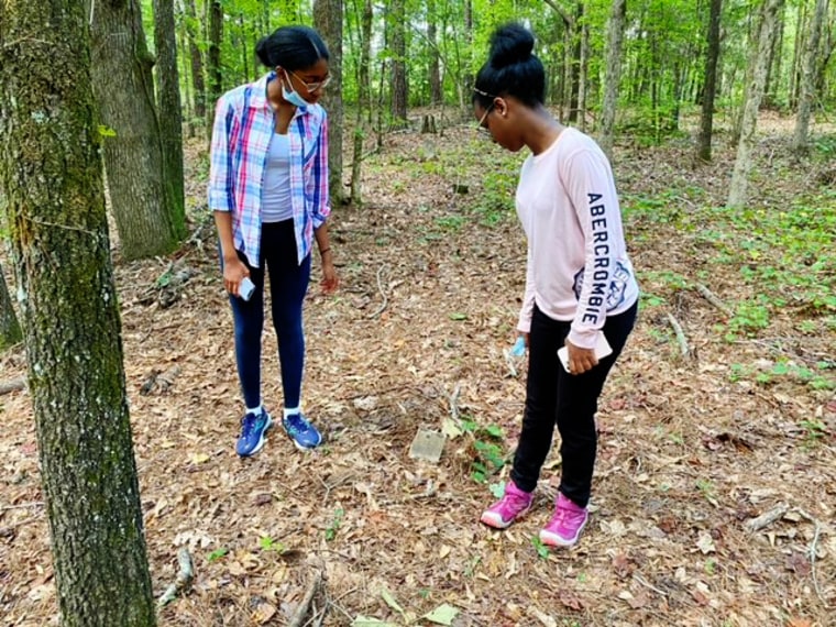 Hannah and Leah Pierce look at a small headstone inscribed with the name Lucy.