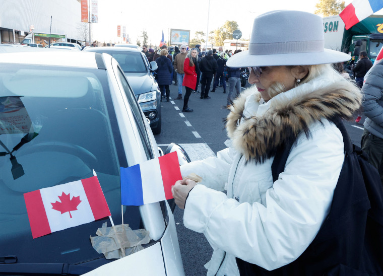 Image: A woman puts Canadian and French flags on her car before the start of The Freedom Convoy in Nice, France, on Feb. 9, 2022.