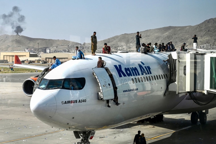 Afghan people climb on a Kam Air plane at the airport in Kabul on Aug. 6, 2021.