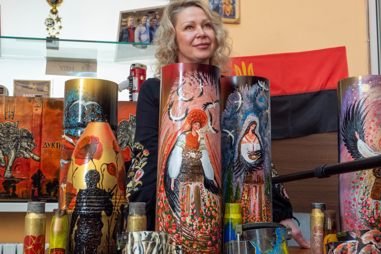 Olena Vovk stands with some of her artwork, which she created from shells and weapon cases. 