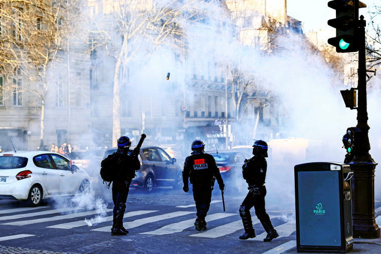 French anti-riot policeman fires a tear gas canister