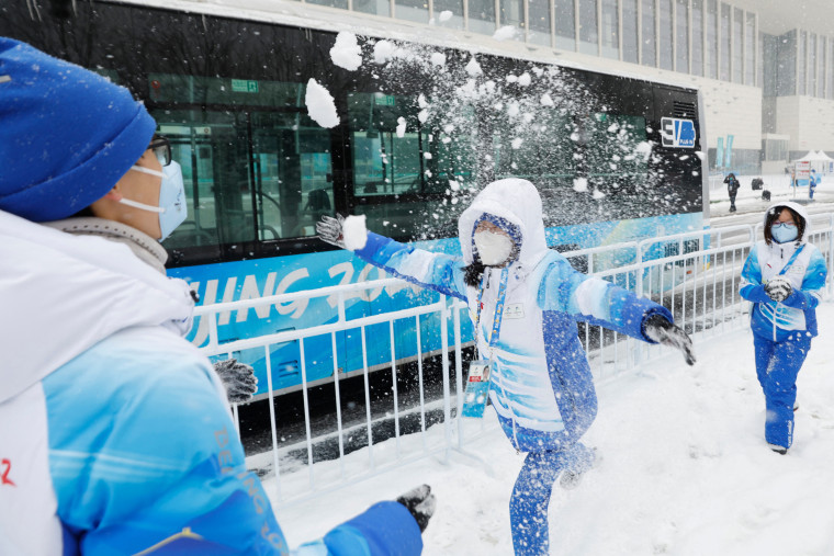Image: Volunteers play in the snow outside the Beijing 2022 Winter Olympics media center in Beijing