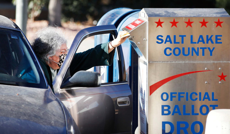 A voter drops off her mail in ballot at a dropbox at the Salt Lake County election office in Utah on October 29, 2020.