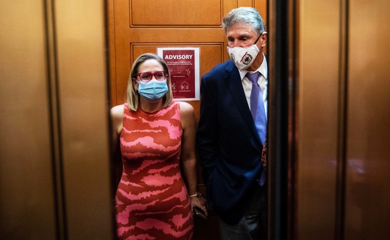 Sen. Kyrsten Sinema and Sen. Joe Manchin catch and an elevator to go to the Senate Chamber to vote, after meeting in Sen. Manchin's hideaway for half an hour in the U.S. Capitol on September 30, 2021 in Washington, DC.