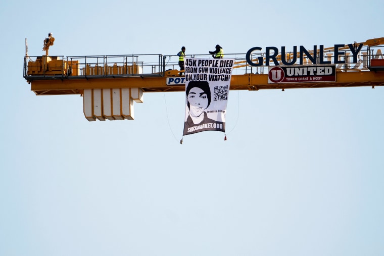 Manuel Oliver displays a banner calling on government officials to prioritize gun violence prevention from a construction crane near the White House on Feb. 14, 2022.