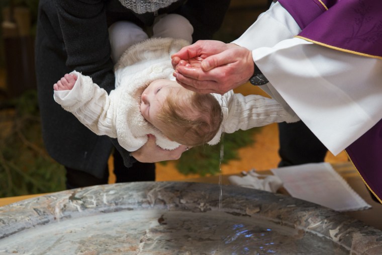 Priest is baptizing little baby girl in a church
