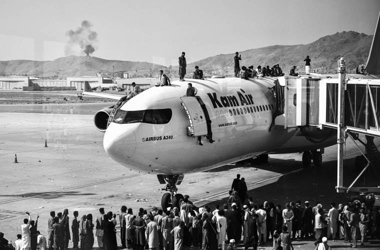 Image: People climb atop a plane as they wait at the airport in Kabul, Afghanistan on Aug. 16, 2021, after a swift end to Afghanistan's 20-year war, as thousands of people mobbed the city's airport.
