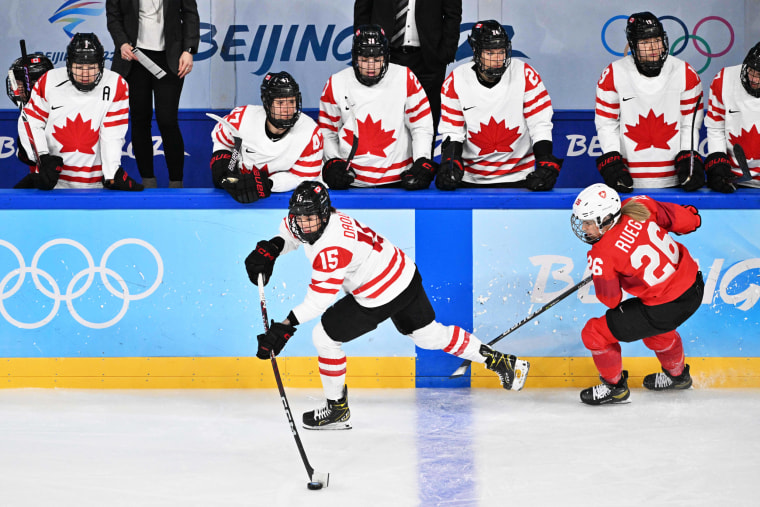 Canada's Melodie Daoust, center, is marked by Switzerland's Dominique Rueegg during the women's play-offs semifinal match of the Beijing 2022 Winter Olympic Games ice hockey competition on Feb. 14, 2022.