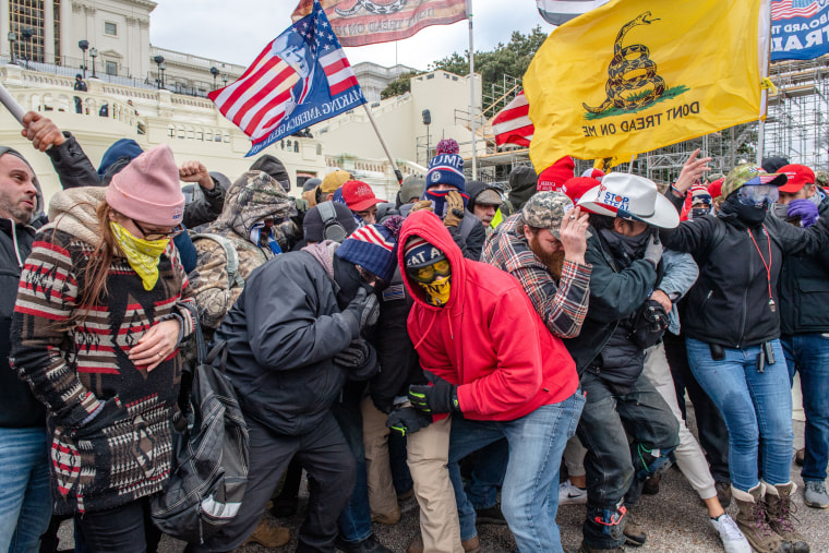 Trump supporters, including Banuelos in the white cowboy hat, react to dispersants as they protest outside of the Capitol on Jan. 6, 2021.