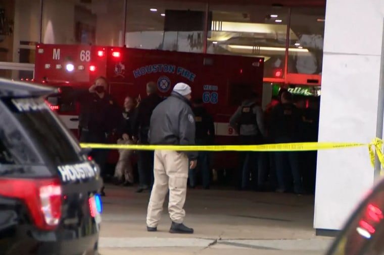 Police and fire personnel stand near a Houston Fire ambulance after a mall shooting.