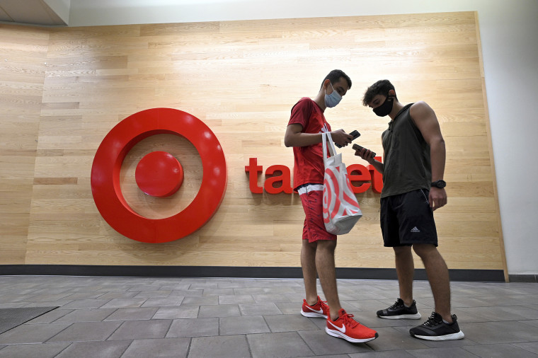 Two men look at their smart phones as they stand outside a Target retail store in Queens, N.Y., on Aug. 12, 2021.