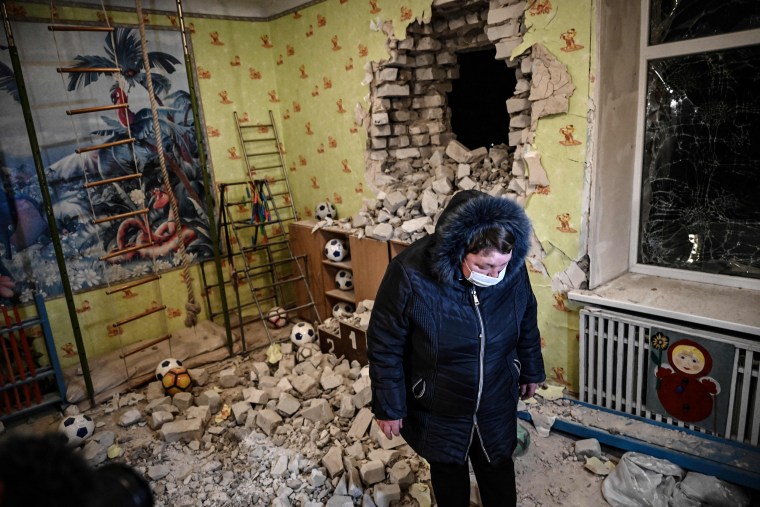 A woman stands among debris of the reported shelling of a kindergarten