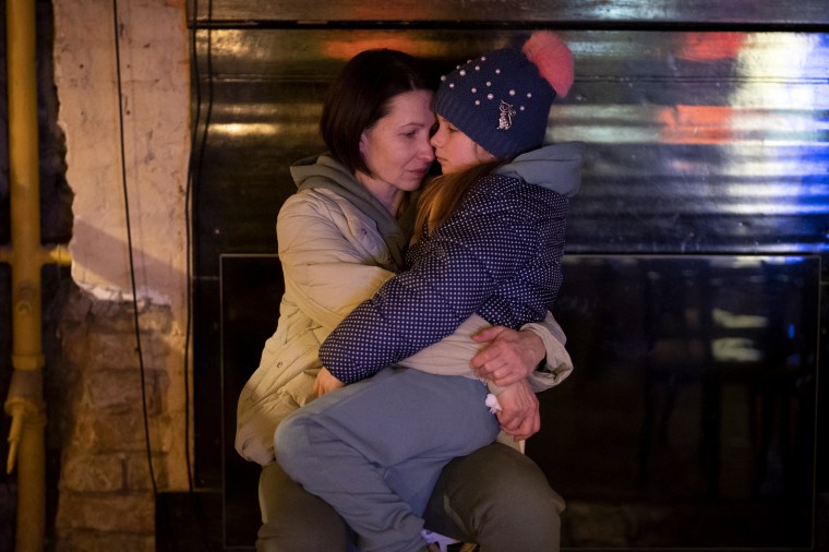 A woman holds her daughter as they sit at a basement used as a bomb shelter in Kyiv. 