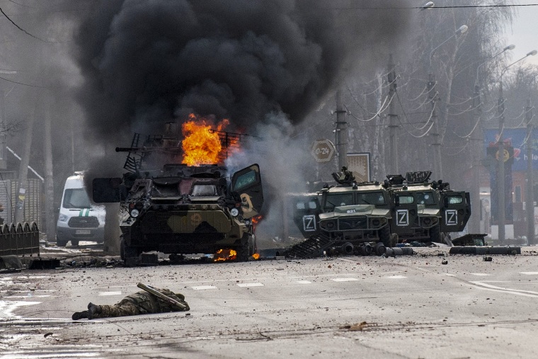 An armored personnel carrier burns and damaged light utility vehicles stand abandoned after fighting in Kharkiv, Ukraine, on Feb. 27, 2022.